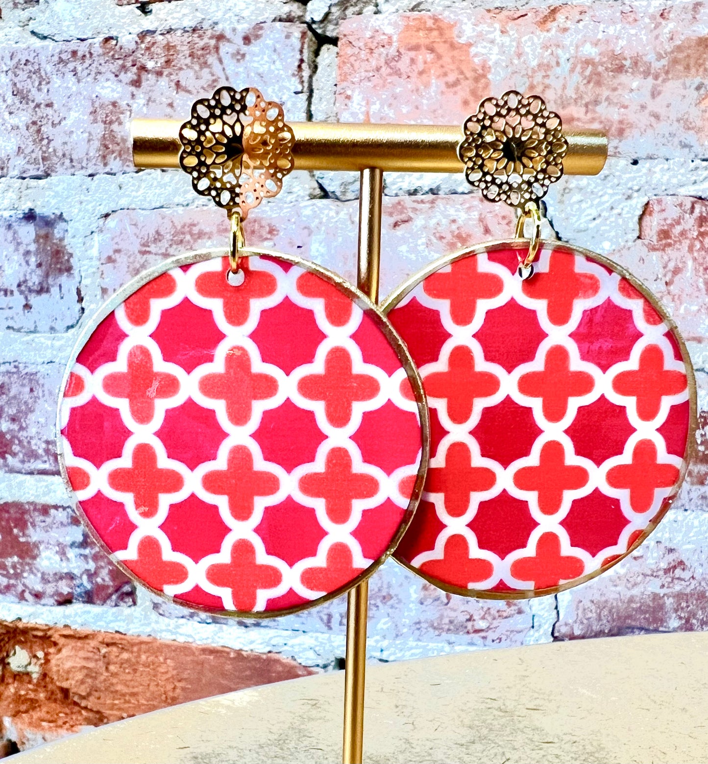 Pink, coral and white cross pattern on round disc with filigree stud.